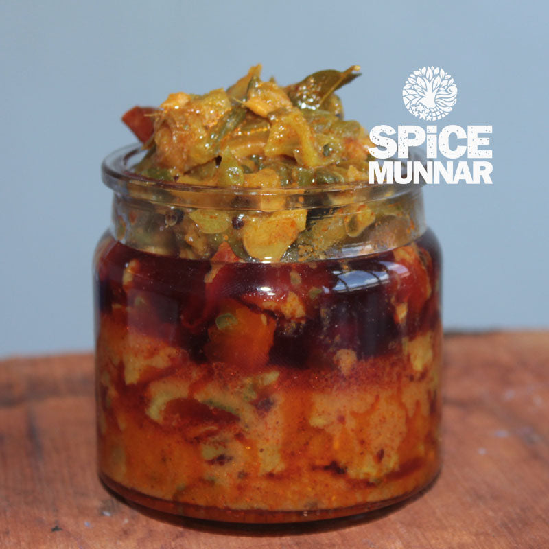Jar of spicy Bitterguard Pickle with 'Spice Munnar' logo on a wooden surface