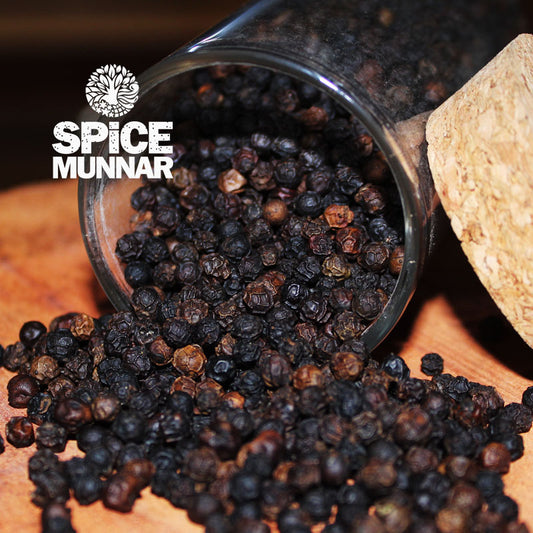 Black peppercorns spilling out of a glass container with 'Spice Munnar' branding  