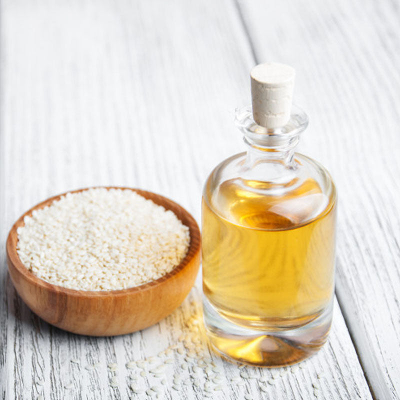 Pure Sesame Oil in a Glass Bottle with Sesame Seeds in a Wooden Bowl